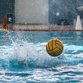 Wasserball beim Spiel als Aufsetzer springt mit vielen Wasserspritzern ab